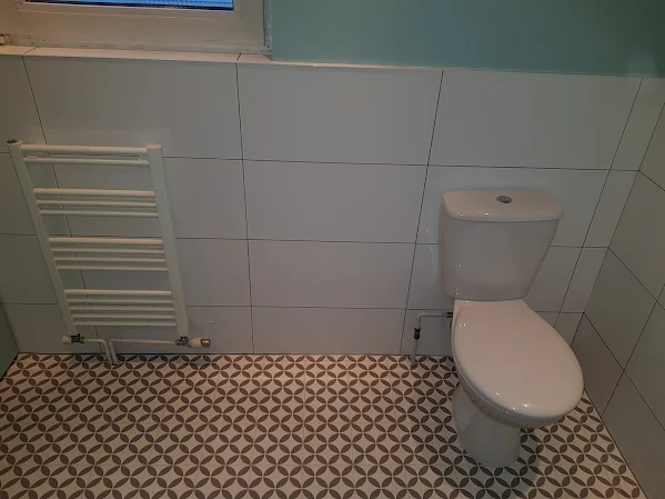 White tiled bathroom with heated towel rail and patterned floor