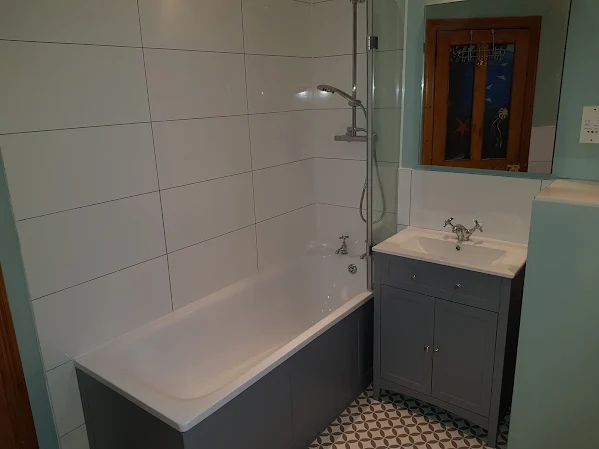Bath with grey vanity unit and white wall tiling