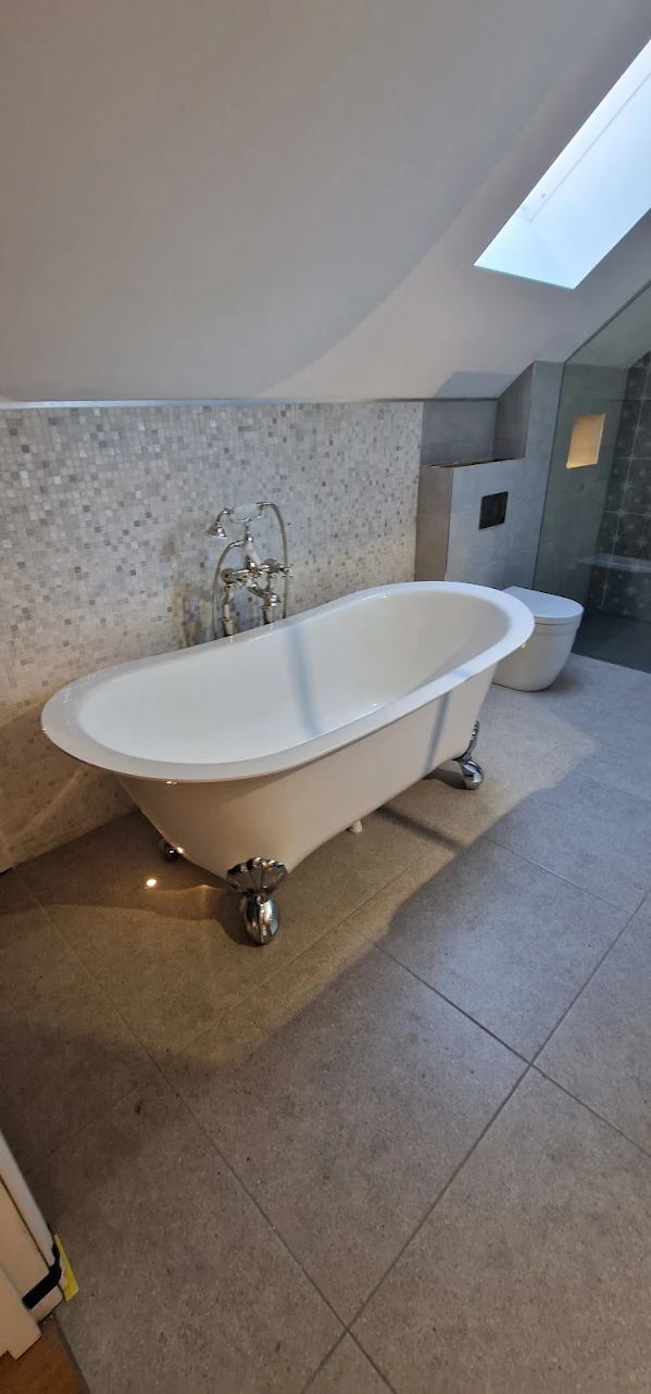 Freestanding roll-top bath in a loft bathroom with patterned feature wall