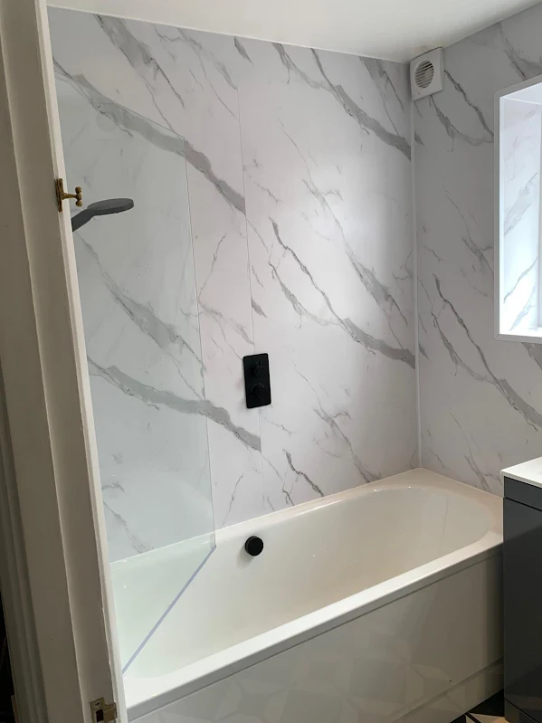 Bath with marble effect wall panels and matt black shower fittings